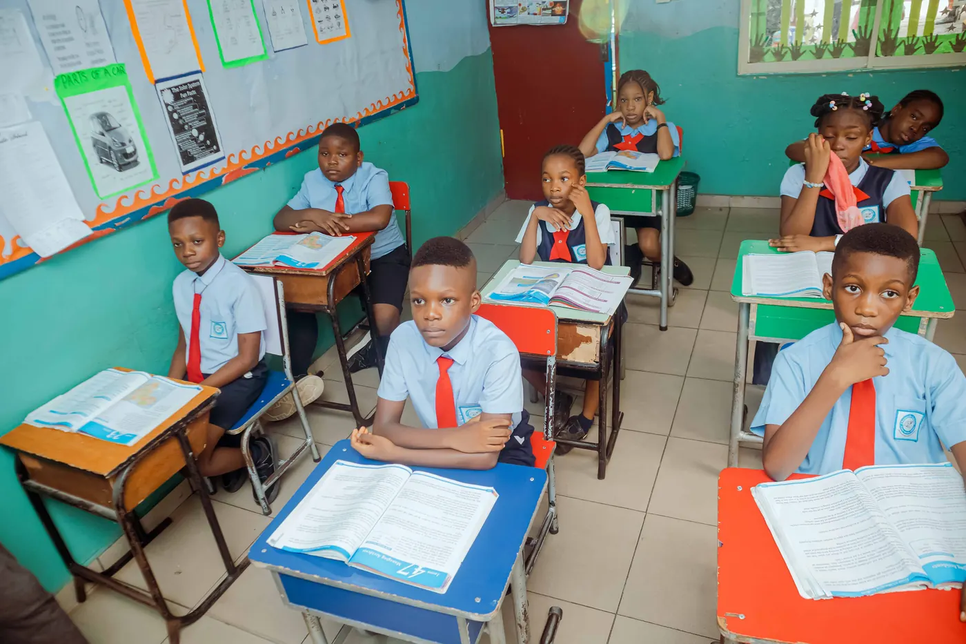 Primary pupils in red ties reading at their desks