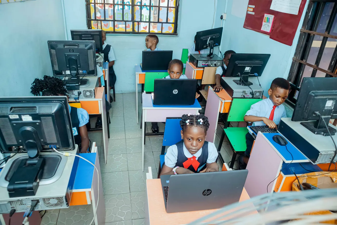 A pupil at a laptop in the Chasteville ICT centre, with rows of computers behind her